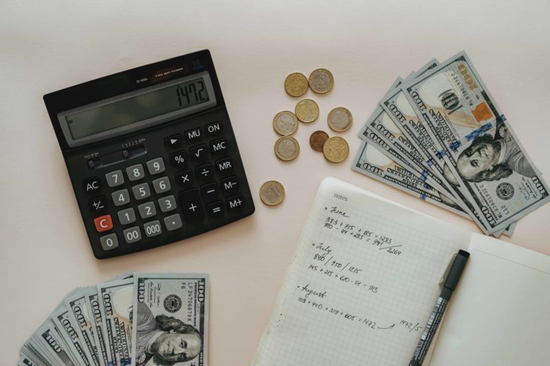 money, calculator and a notepad with notes about finances